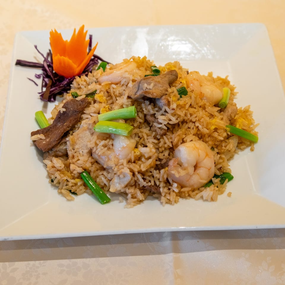 Thai fried rice with shrimp, beef, and green onions, garnished with a carrot flower.