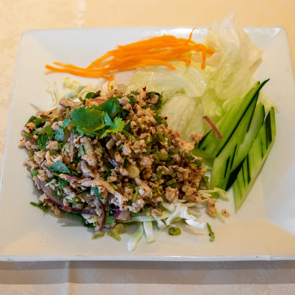 Thai Larb Gai with minced chicken, herbs, shredded carrots, lettuce, and sliced cucumbers.